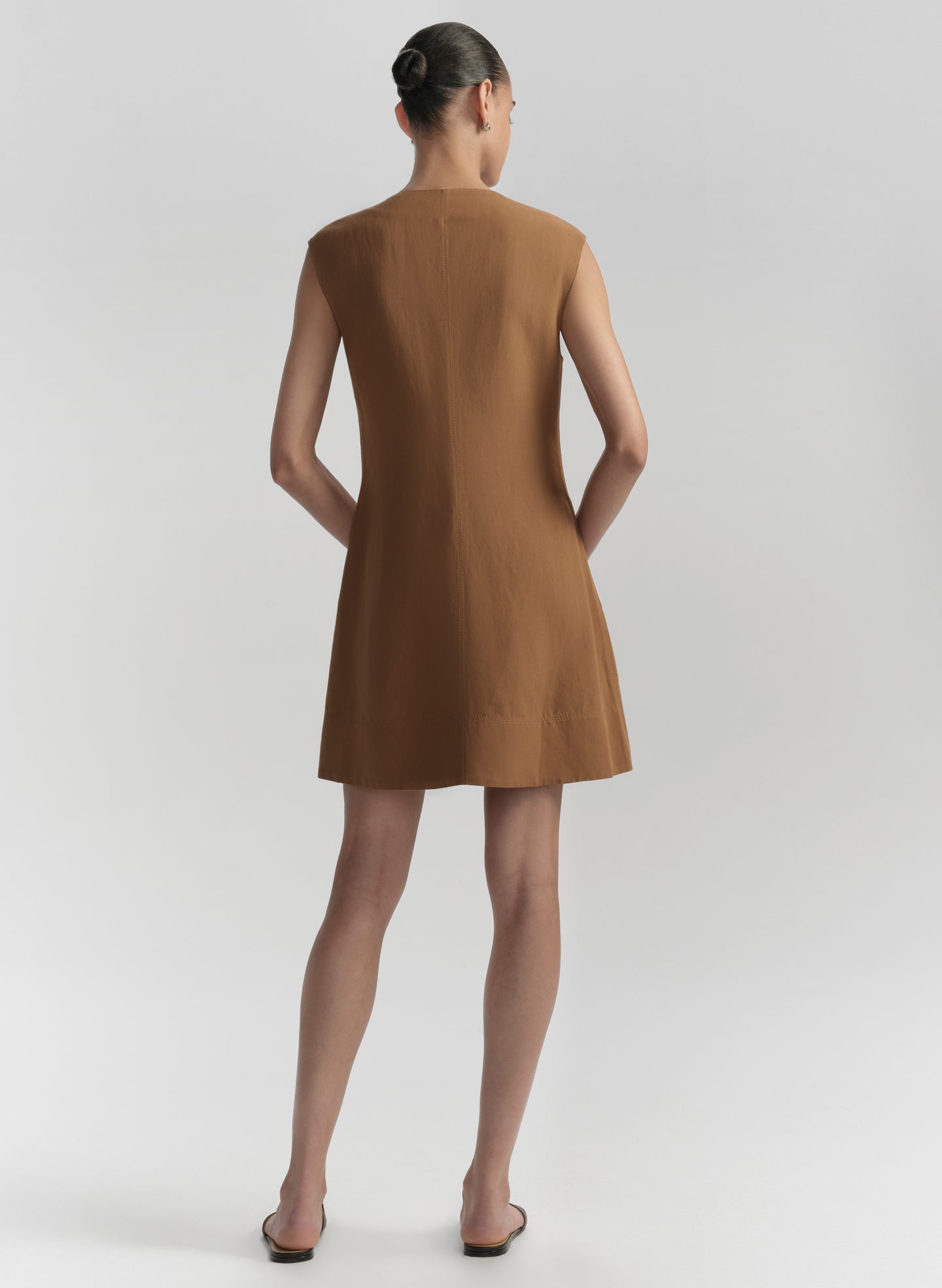 Woman wearing a brown dress against a plain background