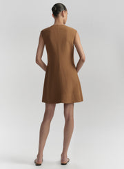 Woman wearing a brown dress against a plain background