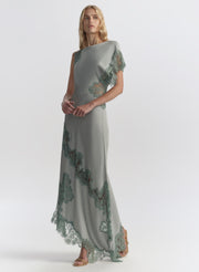 Woman wearing a long, elegant light blue dress with floral lace details on a white background