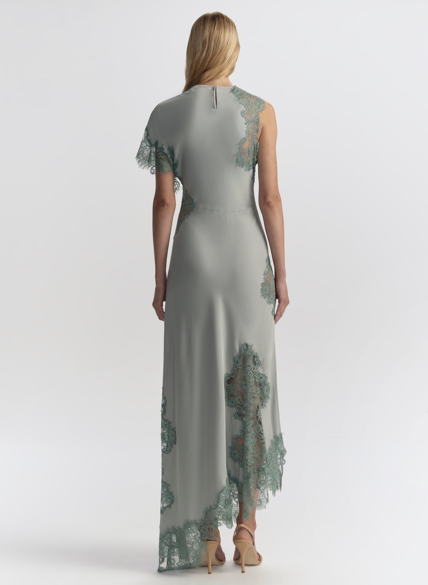 Woman wearing a long, elegant light blue dress with floral lace details on a white background