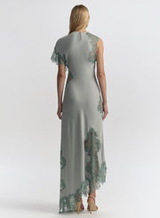 Woman wearing a long, elegant light blue dress with floral lace details on a white background