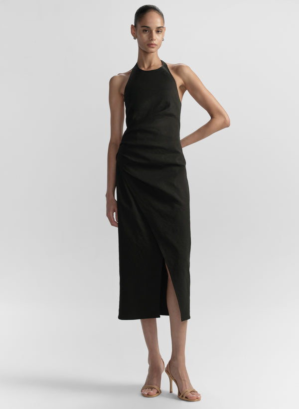 Woman wearing a black halter neck dress on a light gray background