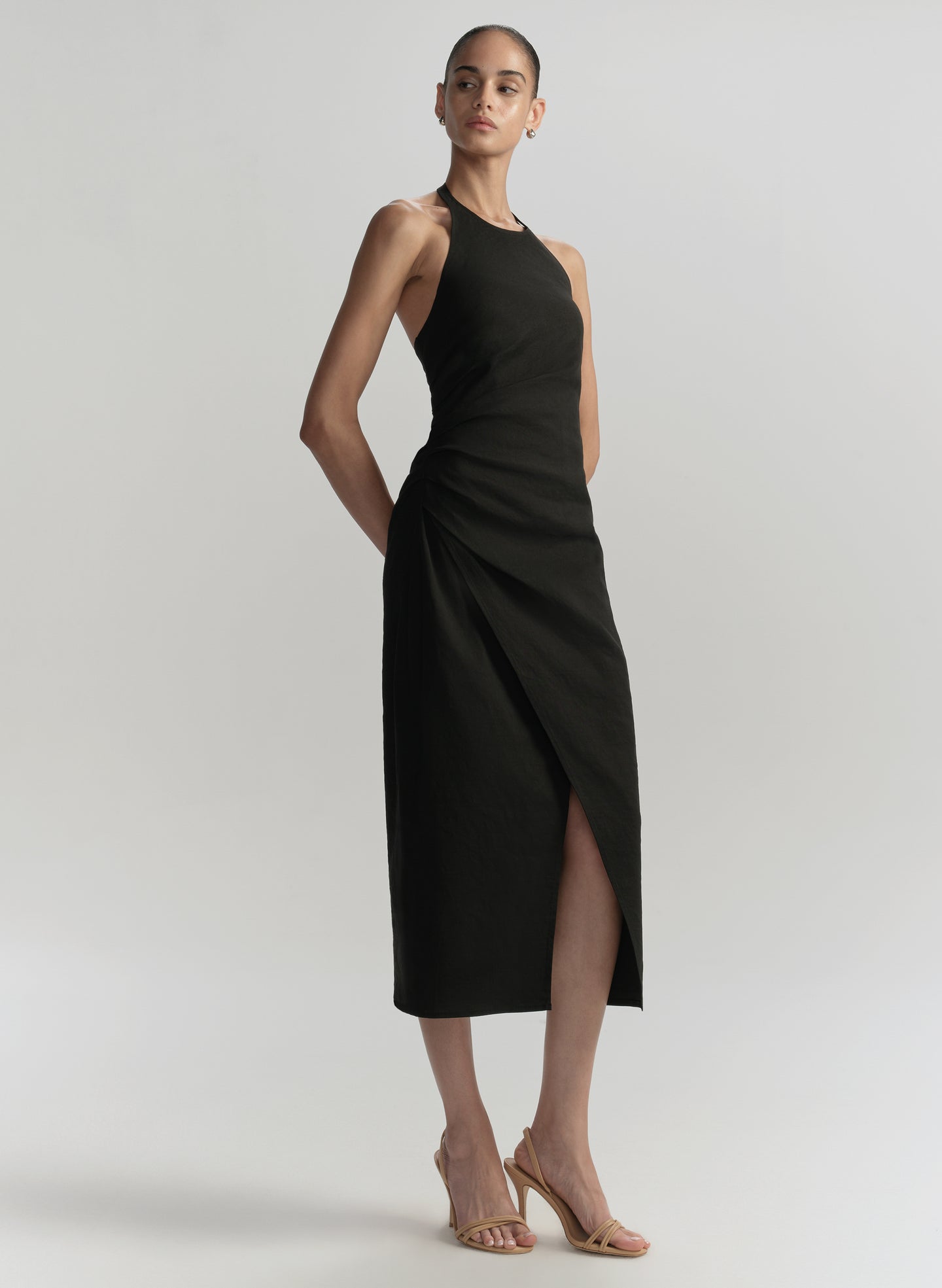 Woman wearing a black halter neck dress on a plain background