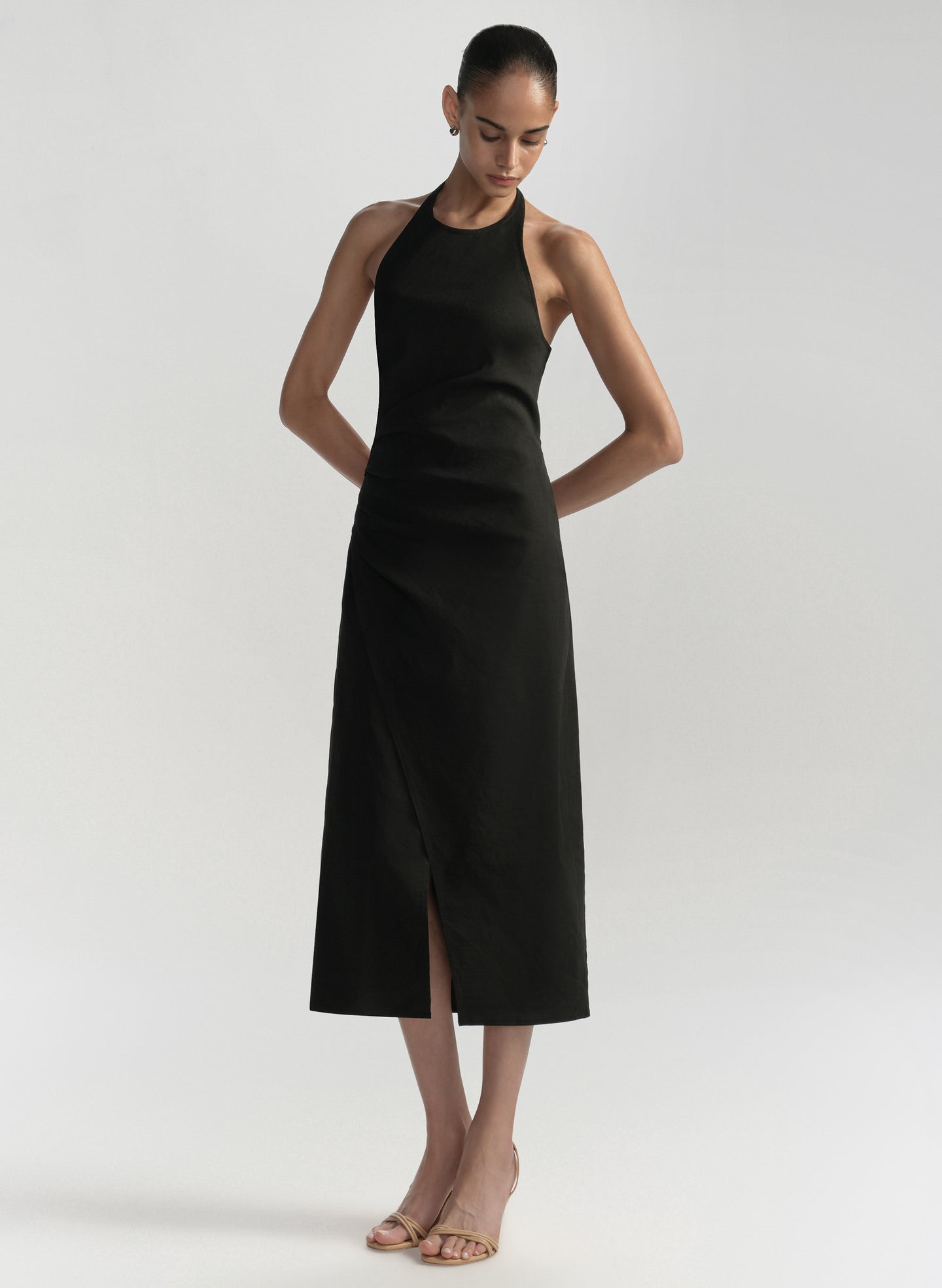 Woman wearing a black halter neck dress on a plain background