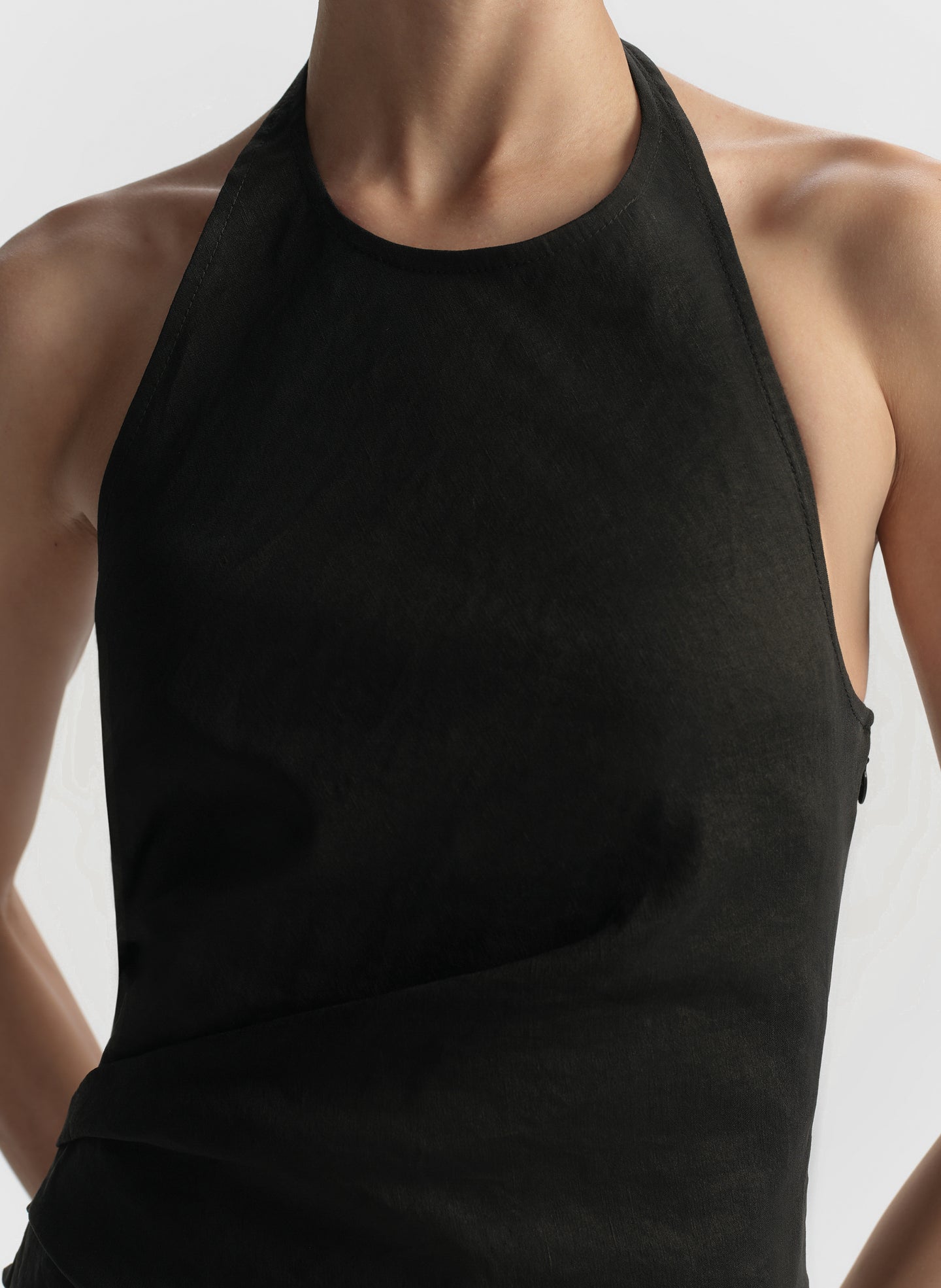 Black halter top worn by a person on a plain background