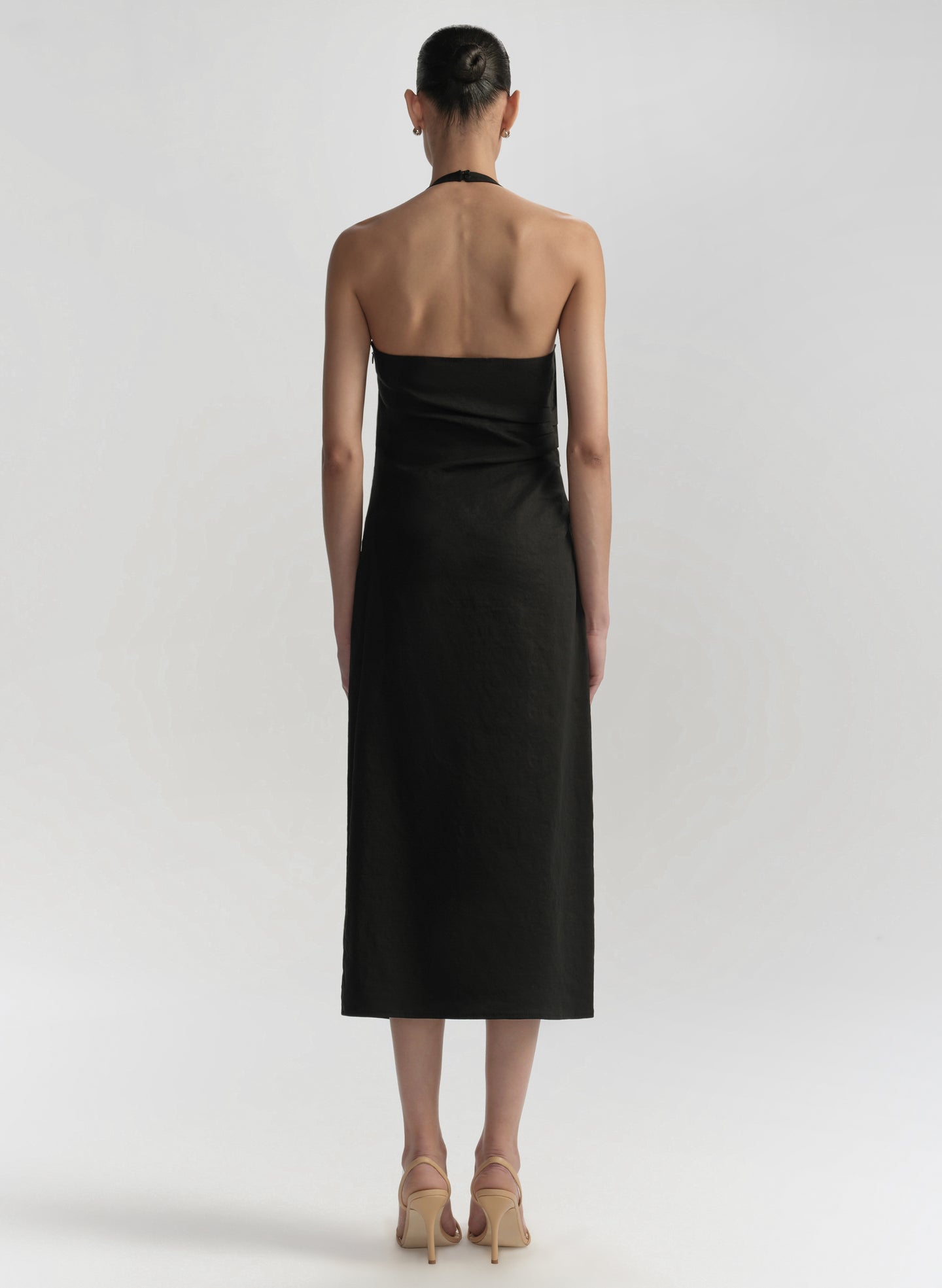 Woman wearing a black halter neck dress on a white background