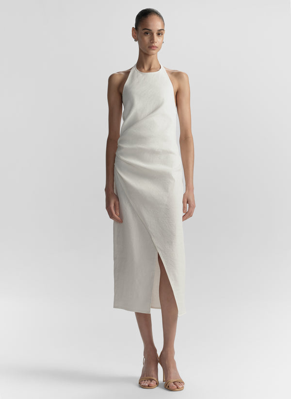 Woman wearing a white halter neck dress on a plain background