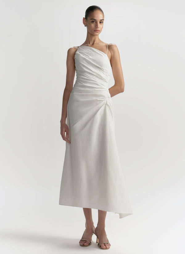 Woman wearing a white one-shoulder dress on a plain background