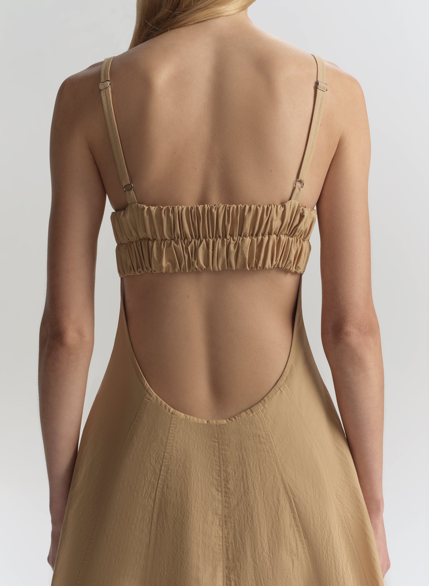 Beige dress with thin straps on a plain background