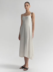 Woman wearing a white sleeveless dress on a plain background