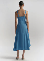 Woman wearing a blue dress with thin straps on a light gray background