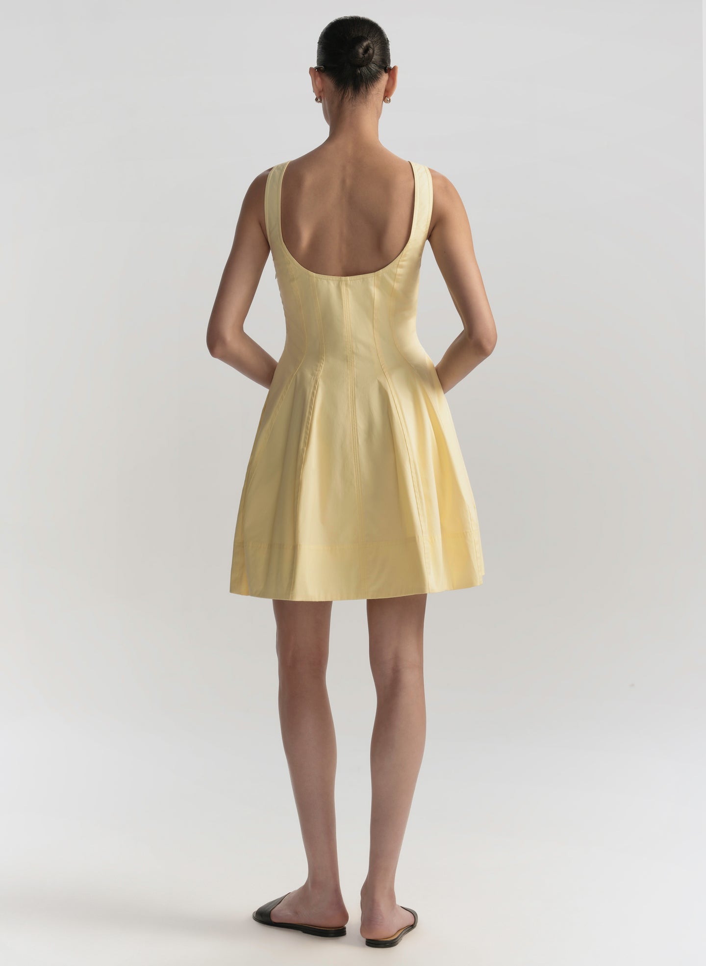 Woman wearing a yellow dress with a plain background