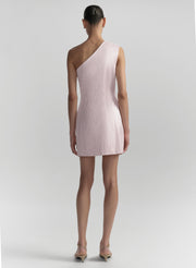 Woman wearing a light pink one-shoulder dress on a plain background