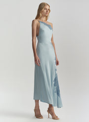 Woman wearing a light blue dress with floral patterns on a plain background