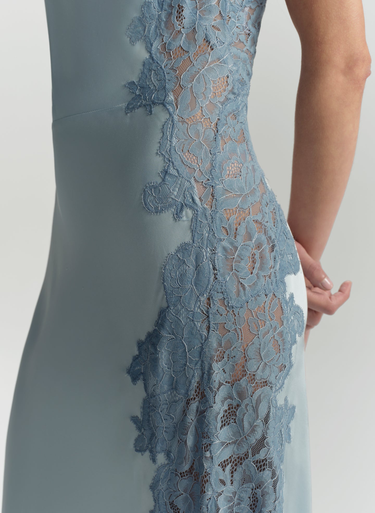Close-up of a blue dress with lace detailing on a plain background