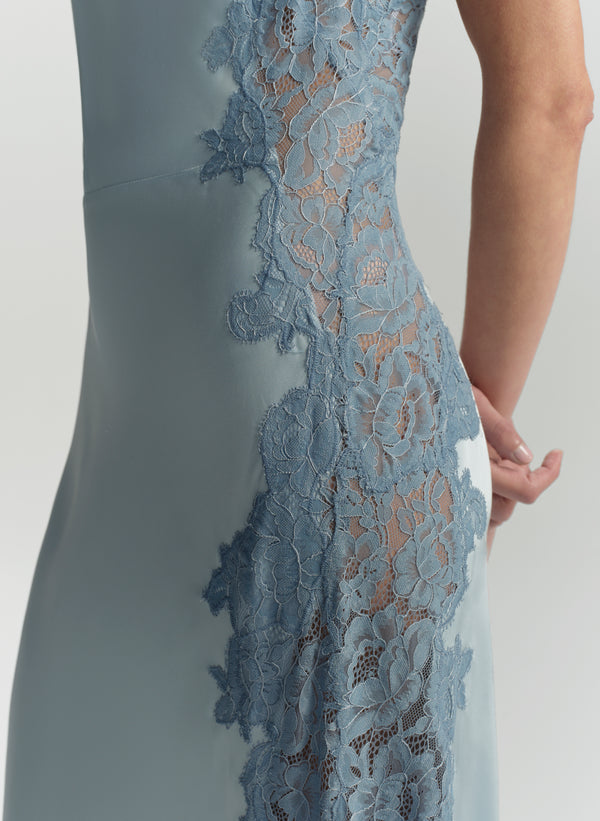 Close-up of a blue dress with lace detailing on a plain background