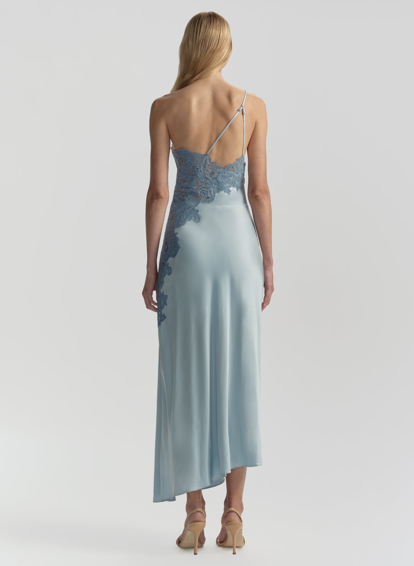 Woman wearing a long, light blue dress with lace detailing on a white background