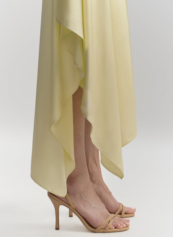 Person wearing a light yellow dress with high-heeled sandals on a white background