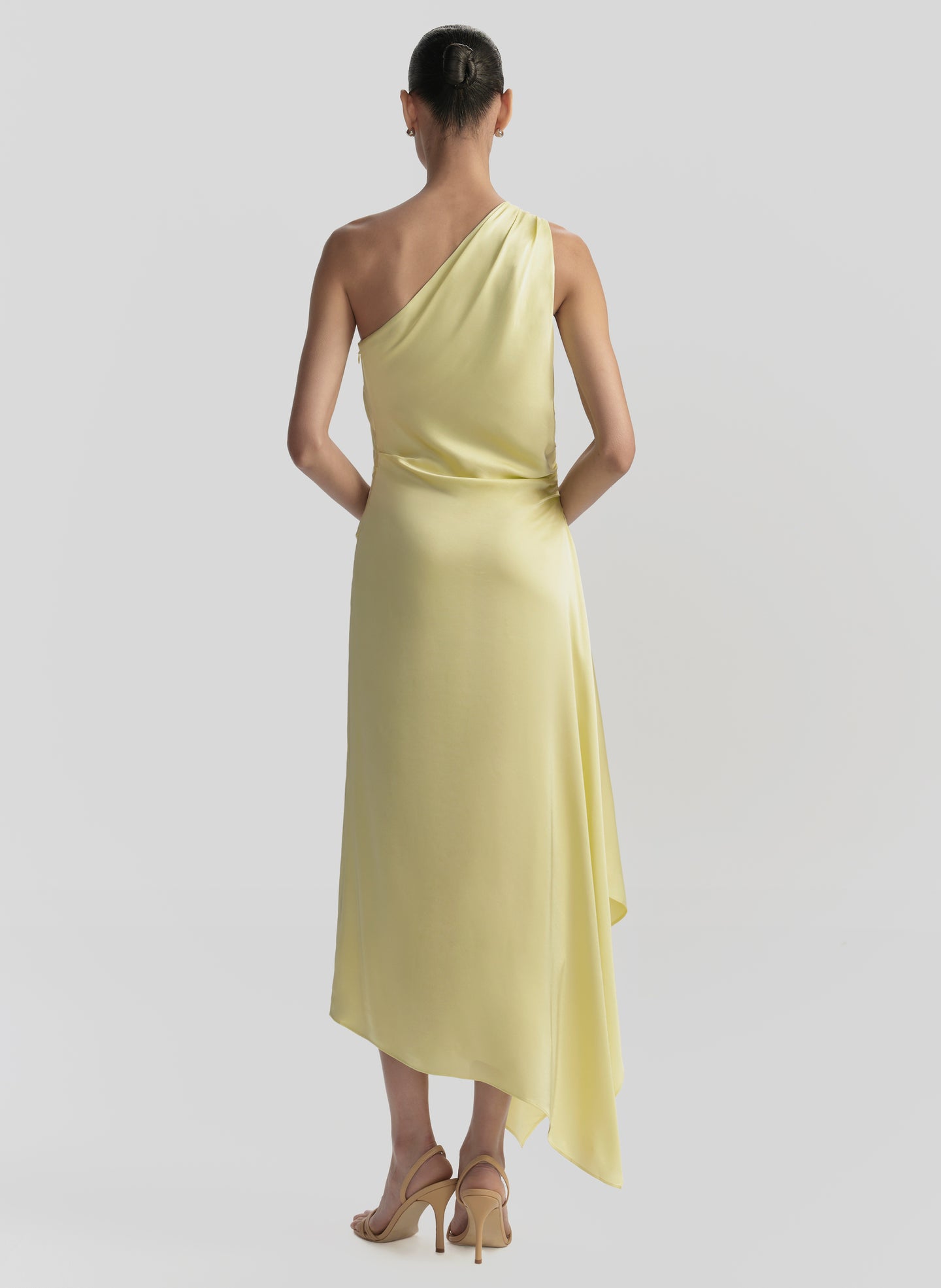 Woman wearing a yellow one-shoulder dress on a light gray background
