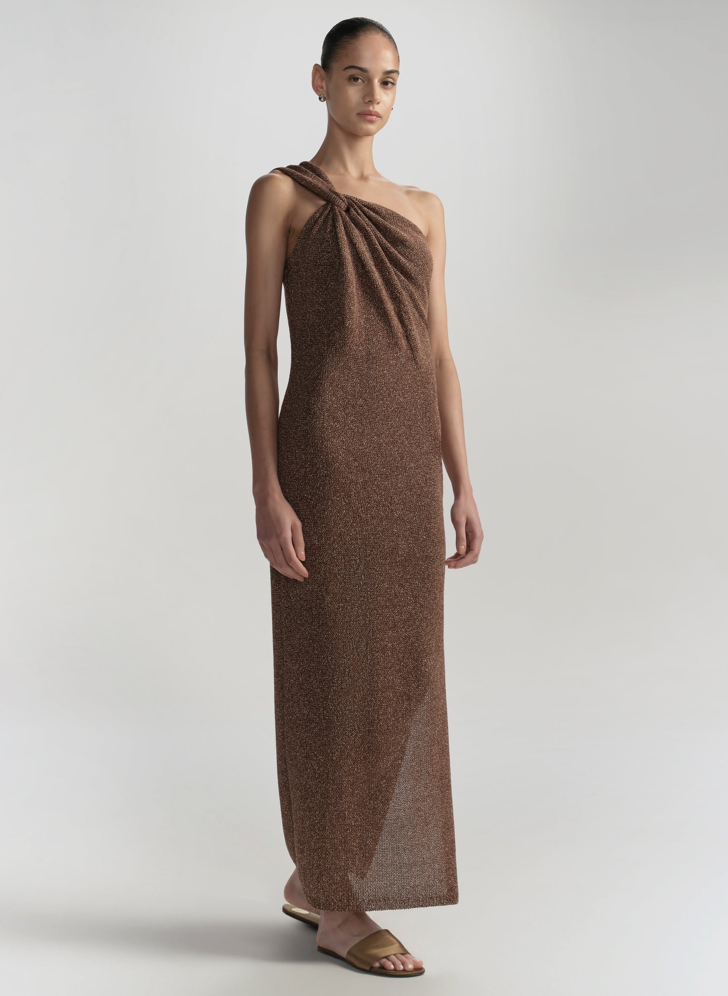 Woman wearing a brown halter neck dress on a plain background