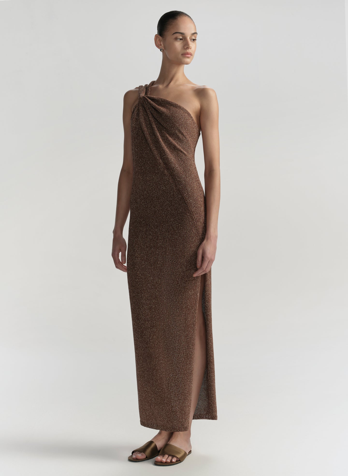 Woman wearing a brown one-shoulder dress on a light gray background