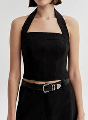 Woman wearing a black halter top and matching shorts with a belt on a light gray background