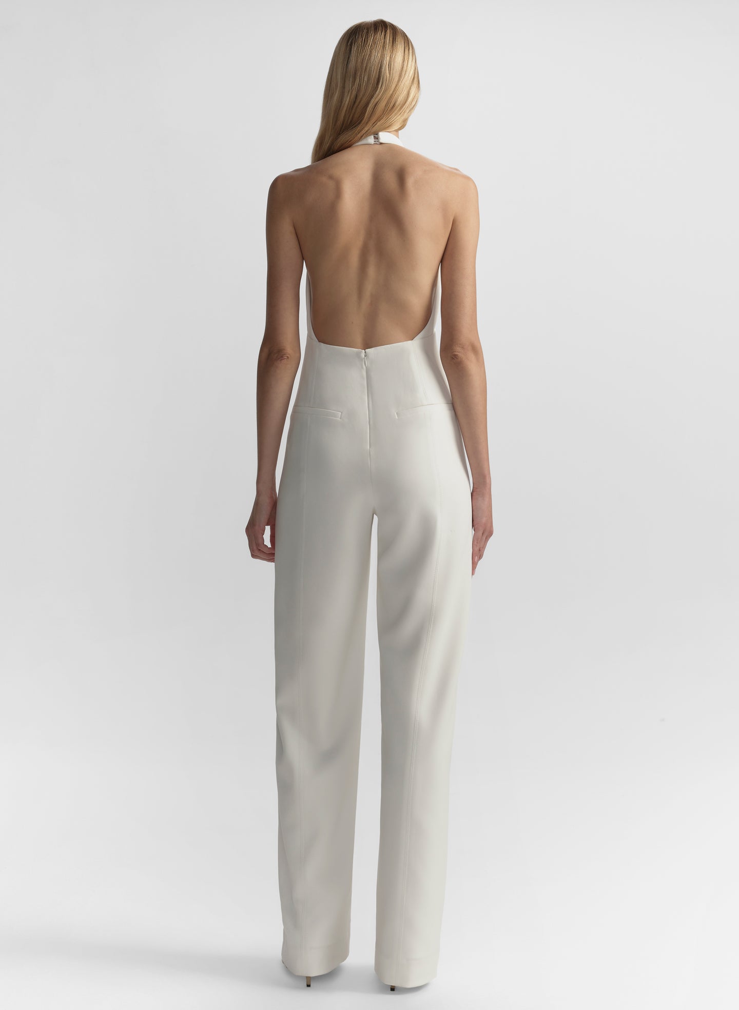 Woman wearing a halter jumpsuit on a plain background