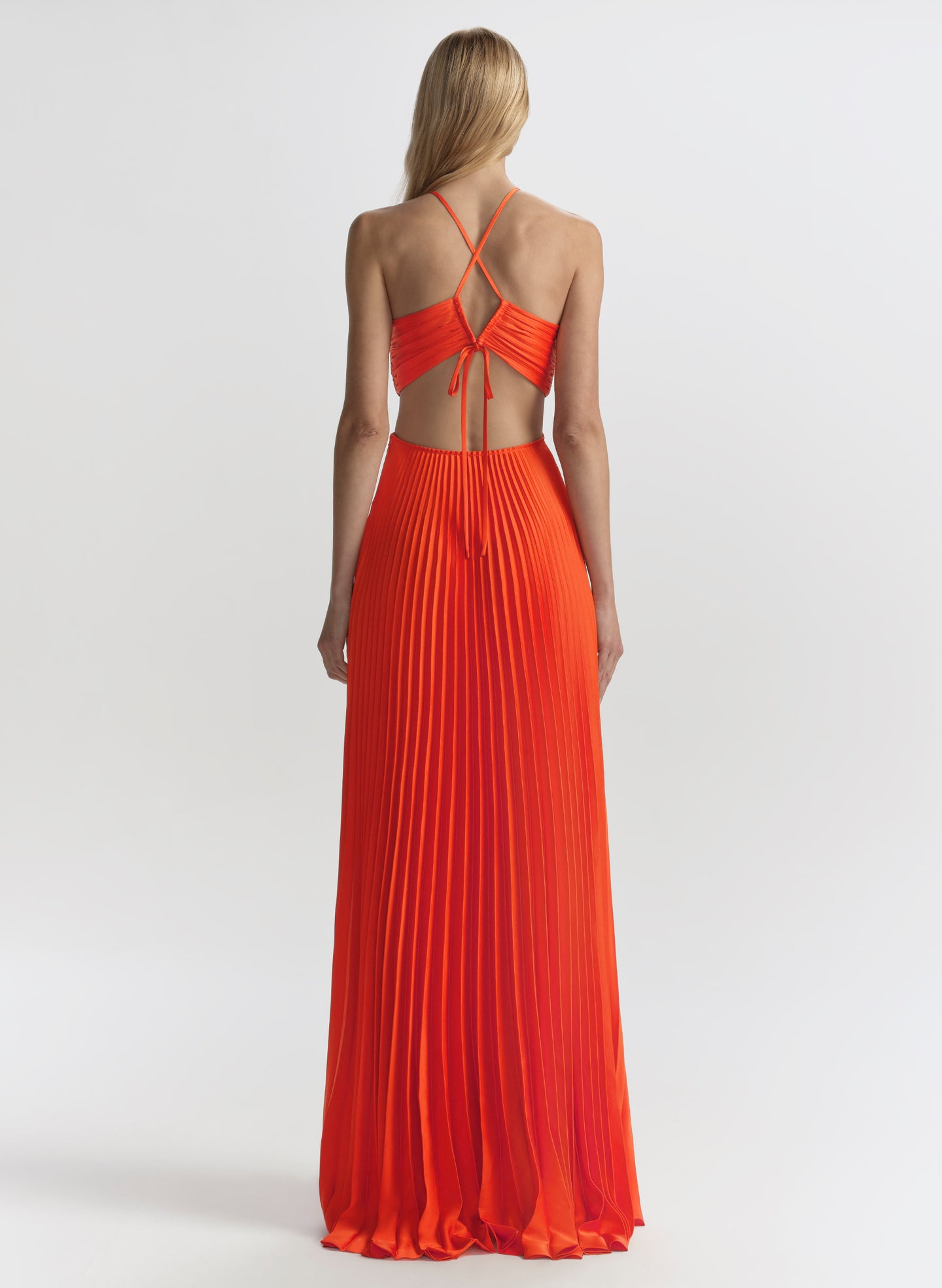Woman wearing a long orange dress with thin straps on a white background