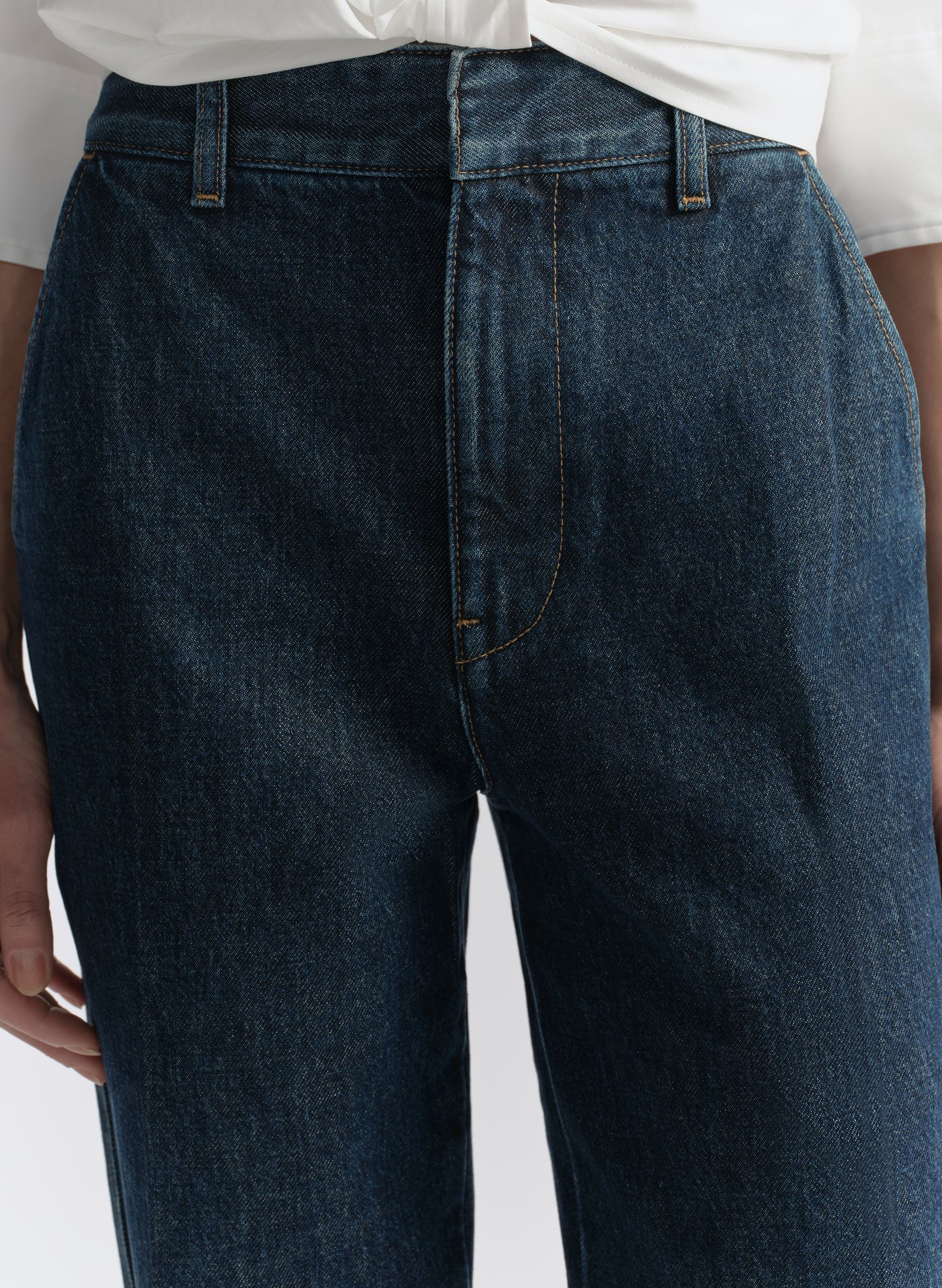 Dark blue jeans worn by a person on a light gray background