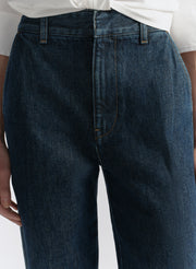 Dark blue jeans worn by a person on a light gray background