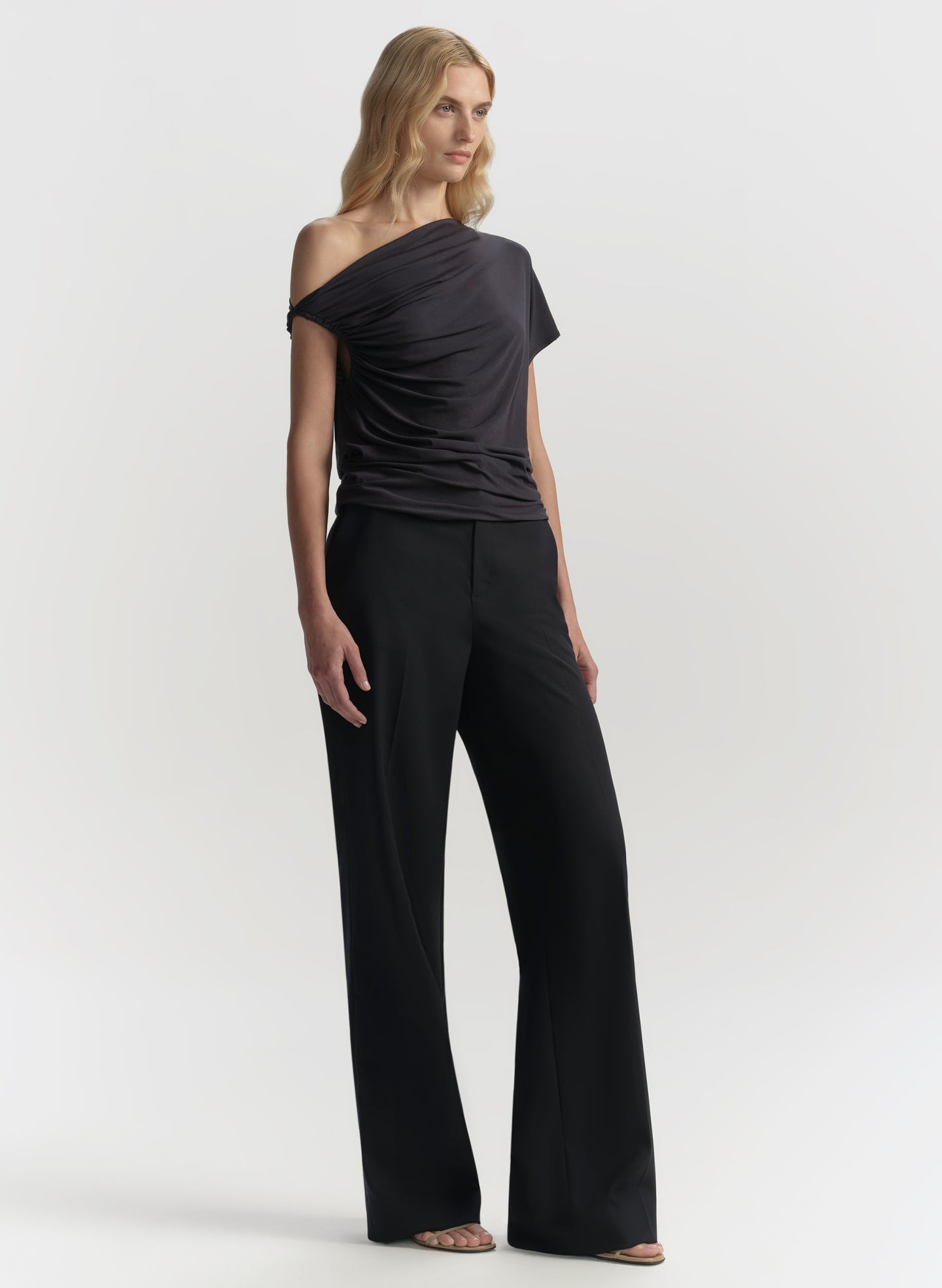 Woman wearing a blue off-shoulder top and wide-leg pants on a white background