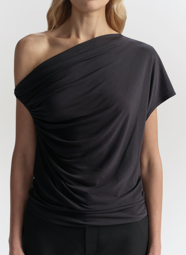 Blue one-shoulder top worn by a model on a white background