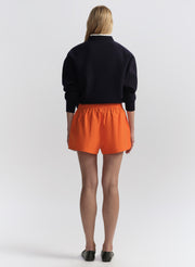 woman wearing a navy blue sweater and orange shorts on a white background