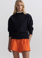 woman wearing navy blue sweater and orange shorts