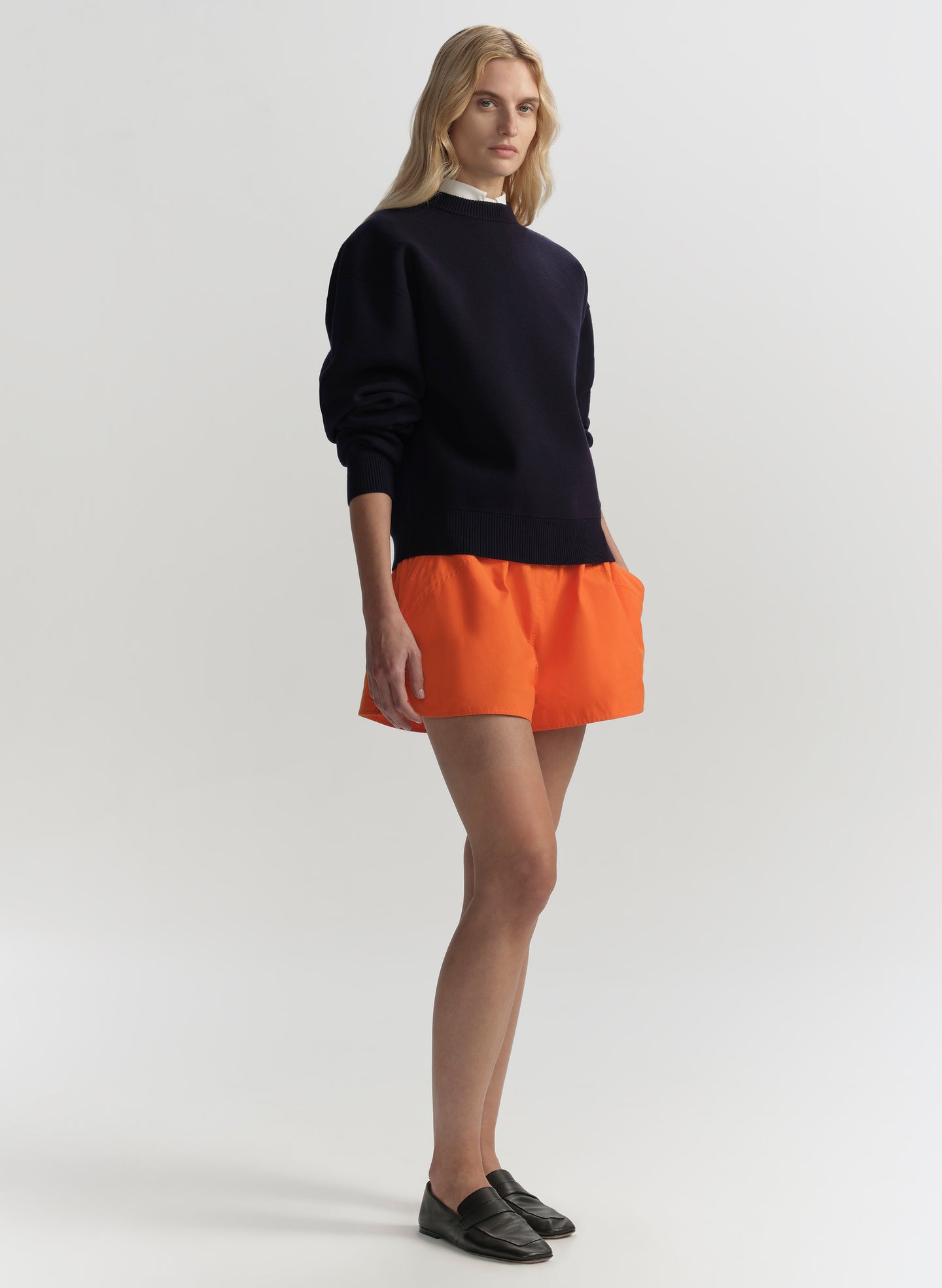 woman wearing navy blue sweater and orange shorts