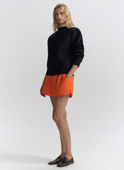 woman wearing navy blue sweater and orange shorts