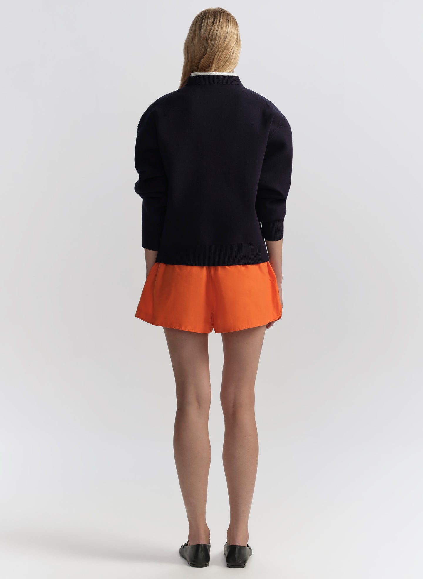 woman wearing navy blue sweater and orange shorts