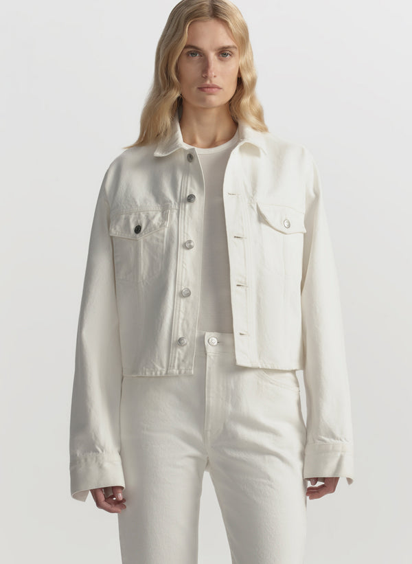 Person wearing a light-colored denim jacket and pants on a white background