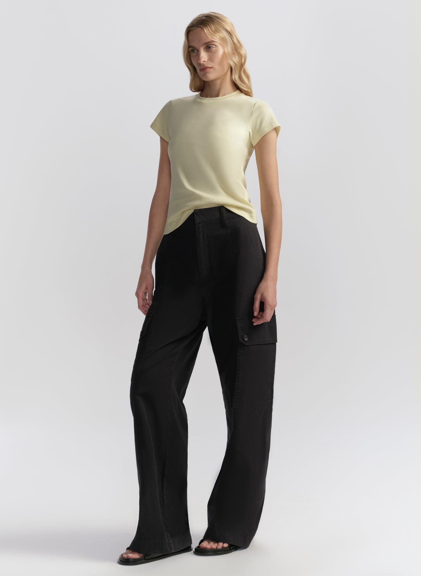 Woman wearing a light yellow t-shirt and blue pants on a white background