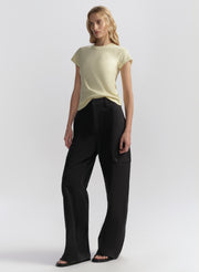 Woman wearing a light yellow t-shirt and blue pants on a white background