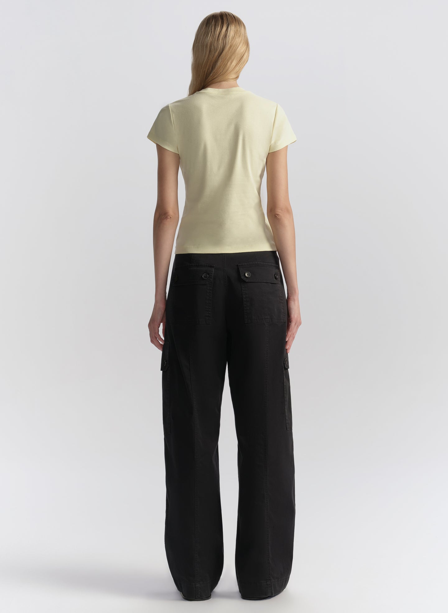 Person wearing a light yellow t-shirt and blue pants on a white background