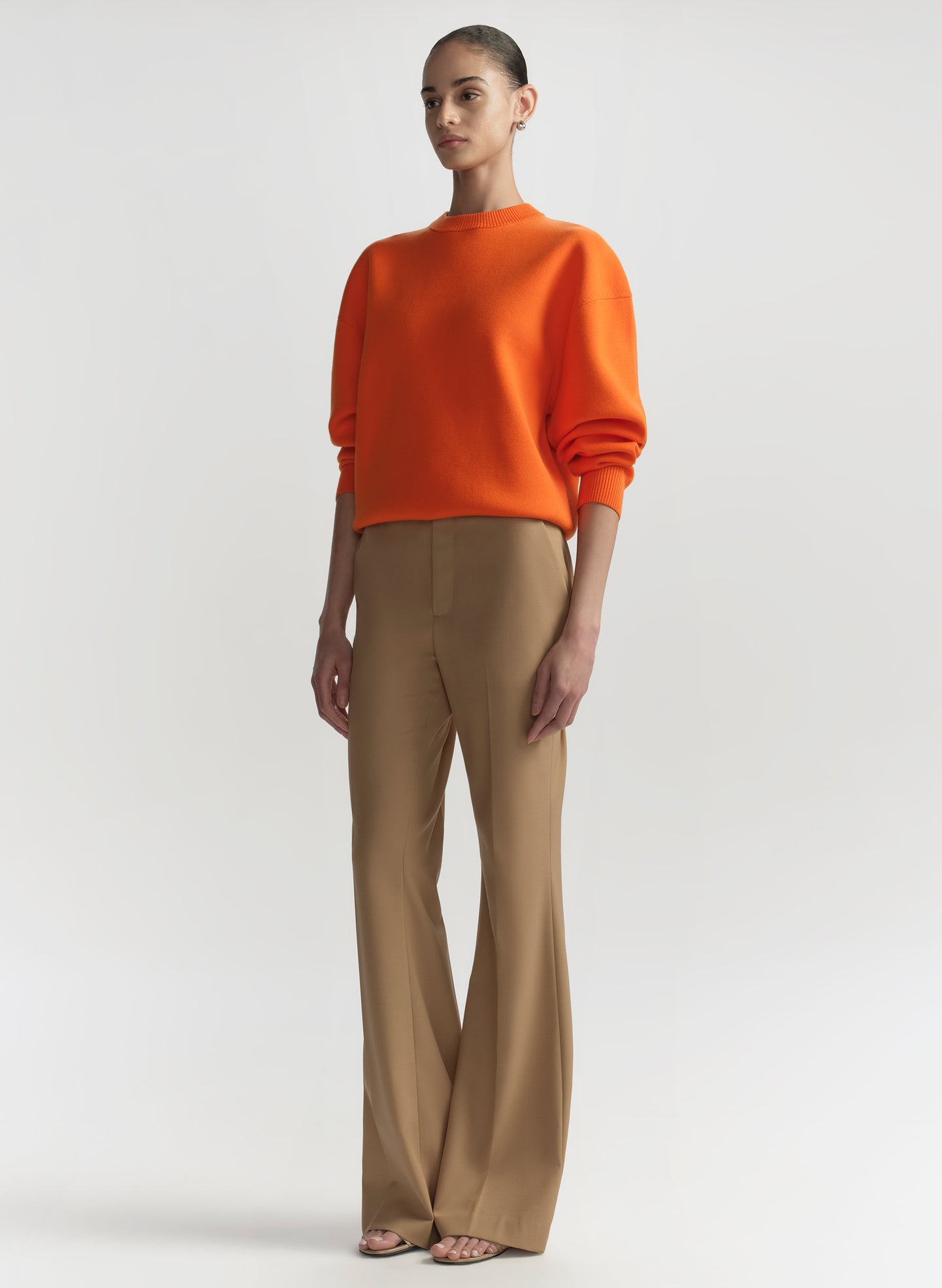 woman wearing orange sweater and tan pants
