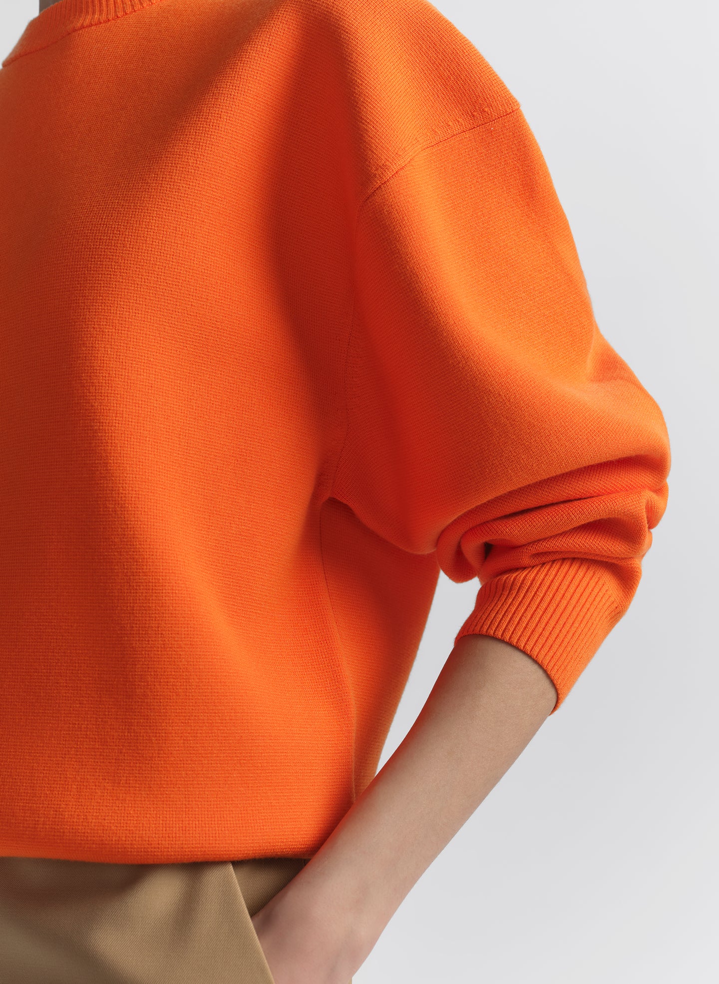 woman wearing orange sweater and tan pants