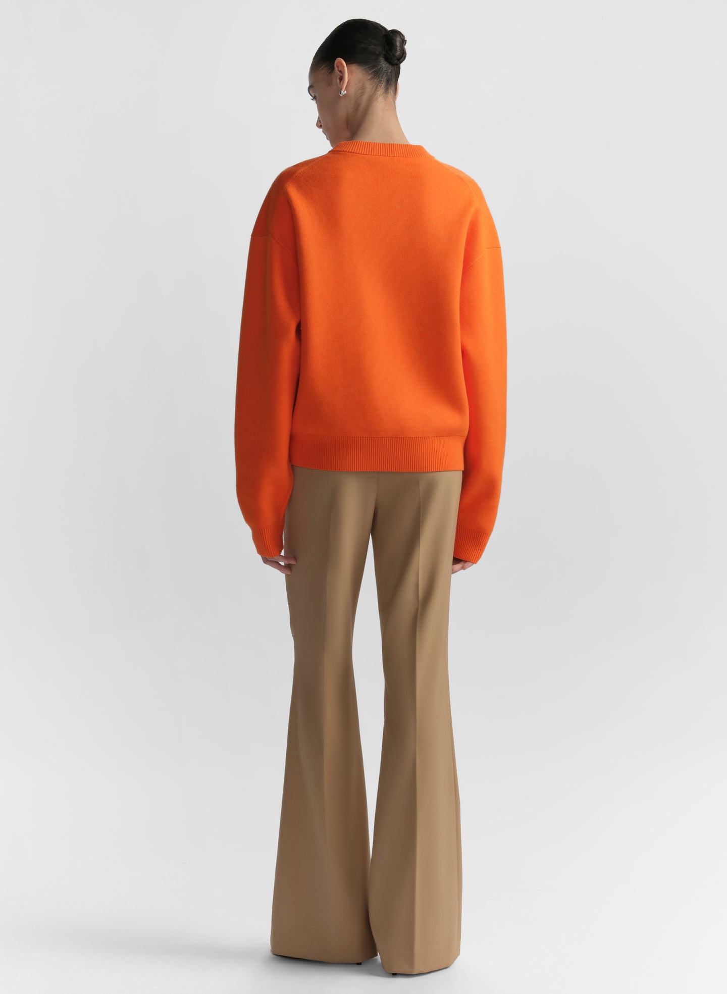 woman wearing orange sweater and tan pants