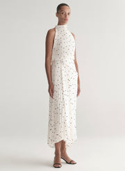 Woman wearing a white dress with black polka dots on a plain background