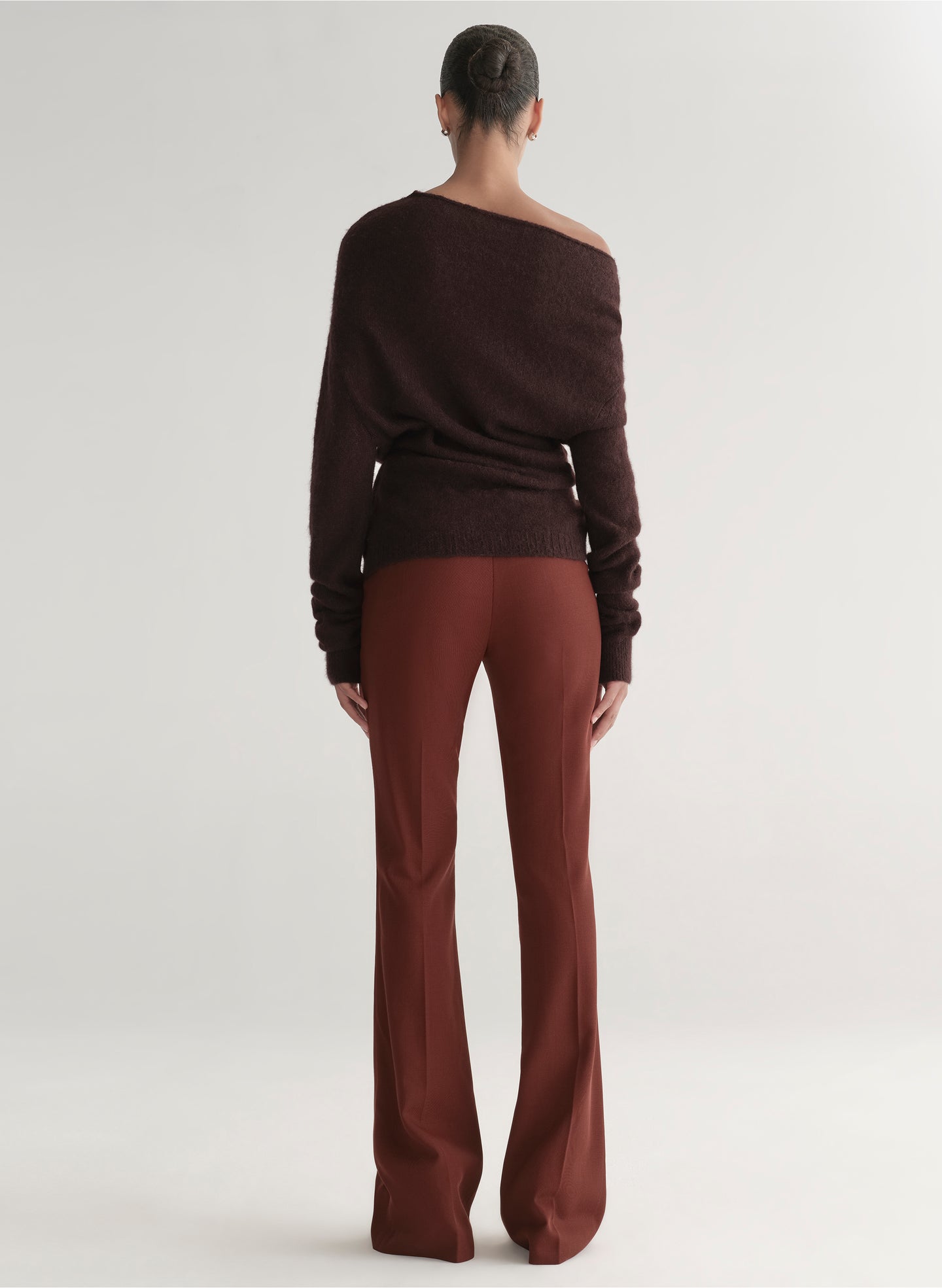 woman wearing a brown off-shoulder top and maroon pants on a white background