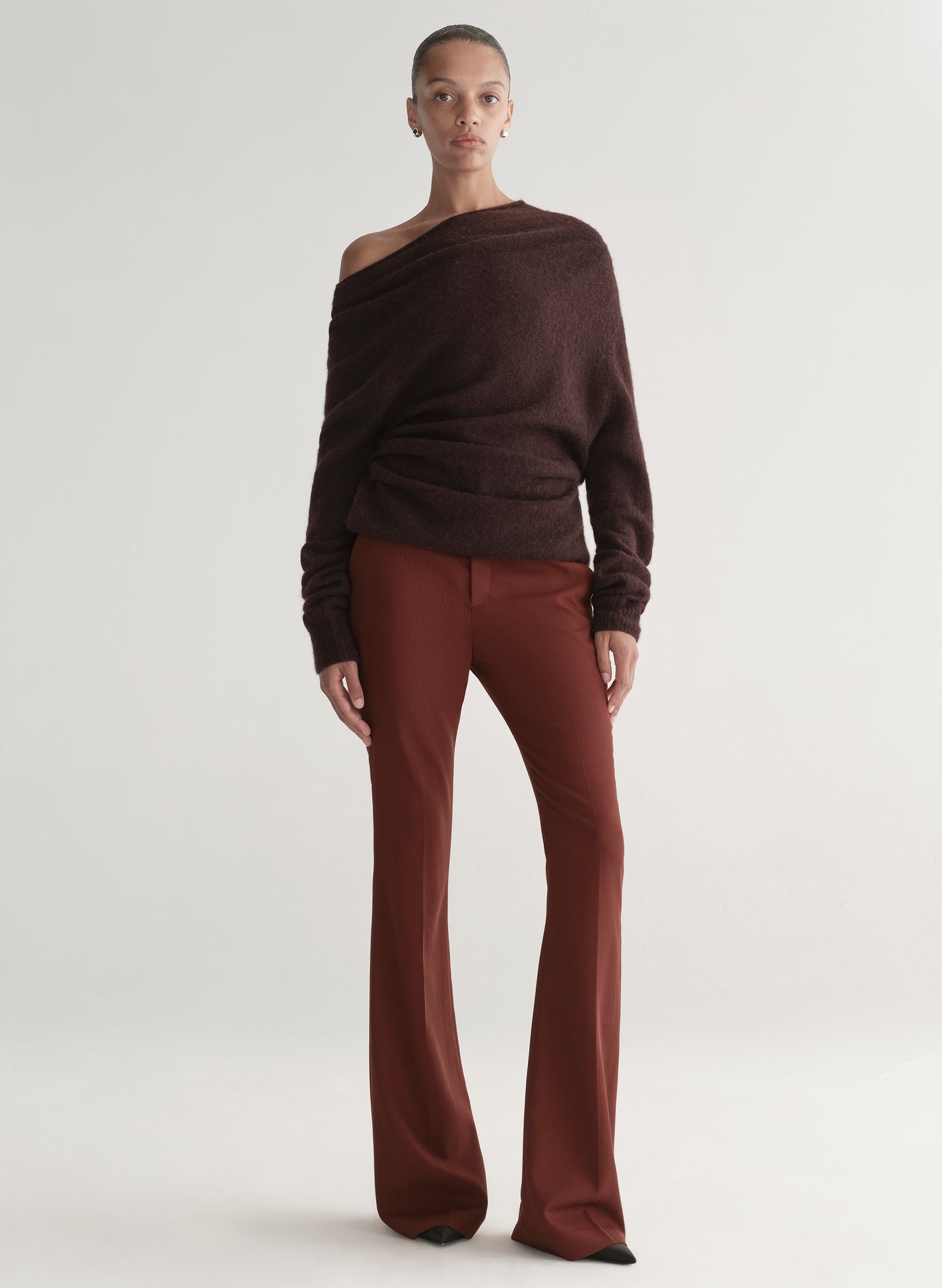 woman wearing a brown off-shoulder top and maroon pants on a white background