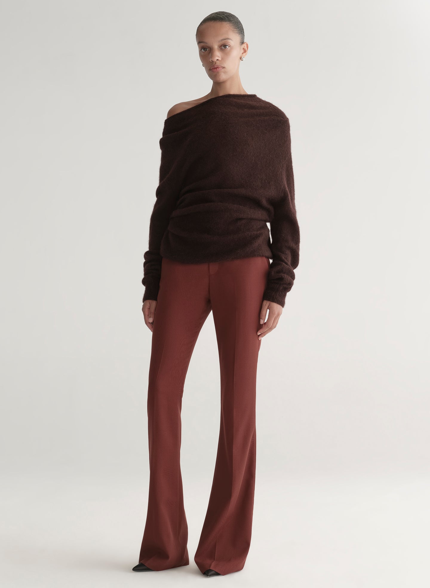 woman wearing a brown off-shoulder top and maroon pants on a white background