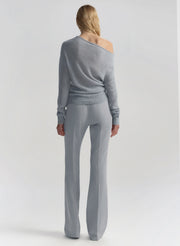 Woman wearing a gray off-shoulder top and matching pants on a light gray background