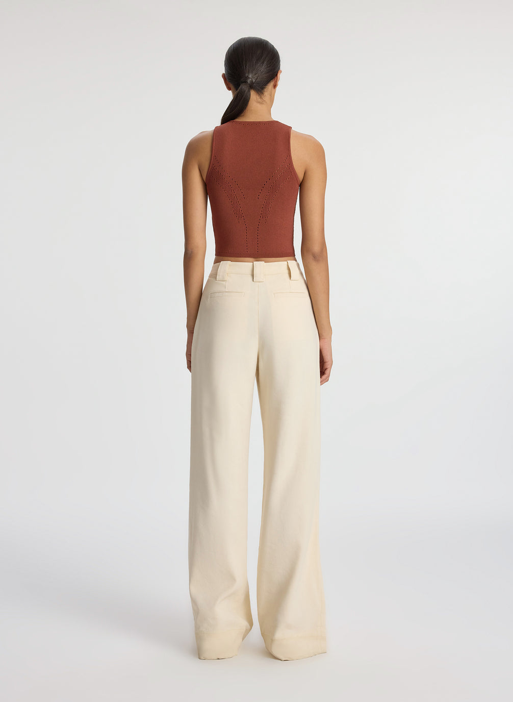 back view of woman wearing brown tank top and beige pants